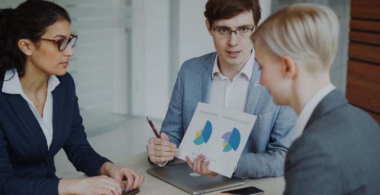 Three professionals discussing charts in a meeting